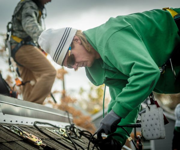 Construction crew installing solar panels on a house